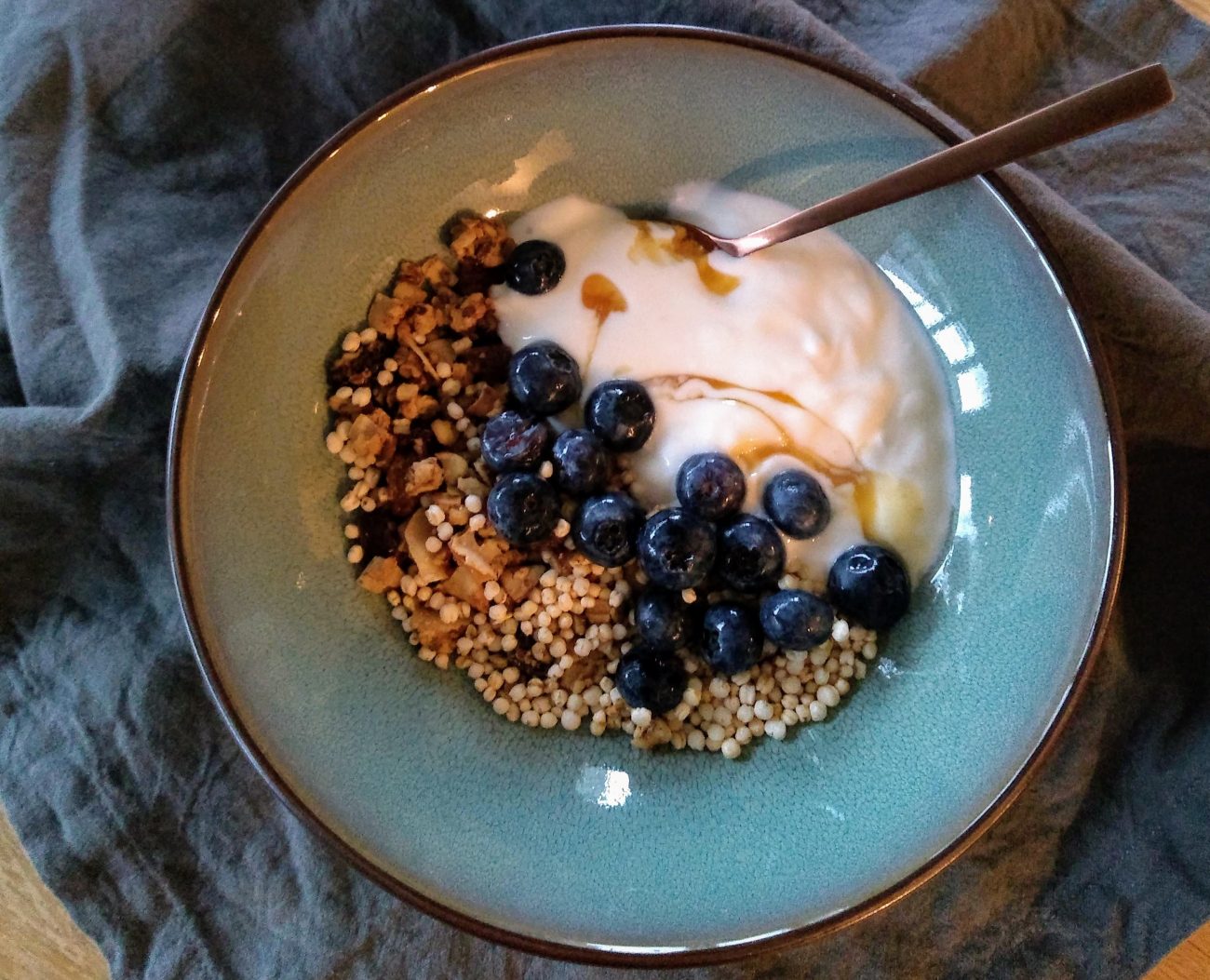 Ontbijt bowl met granola, gepofte quinoa, yoghurt en blauwe bessen